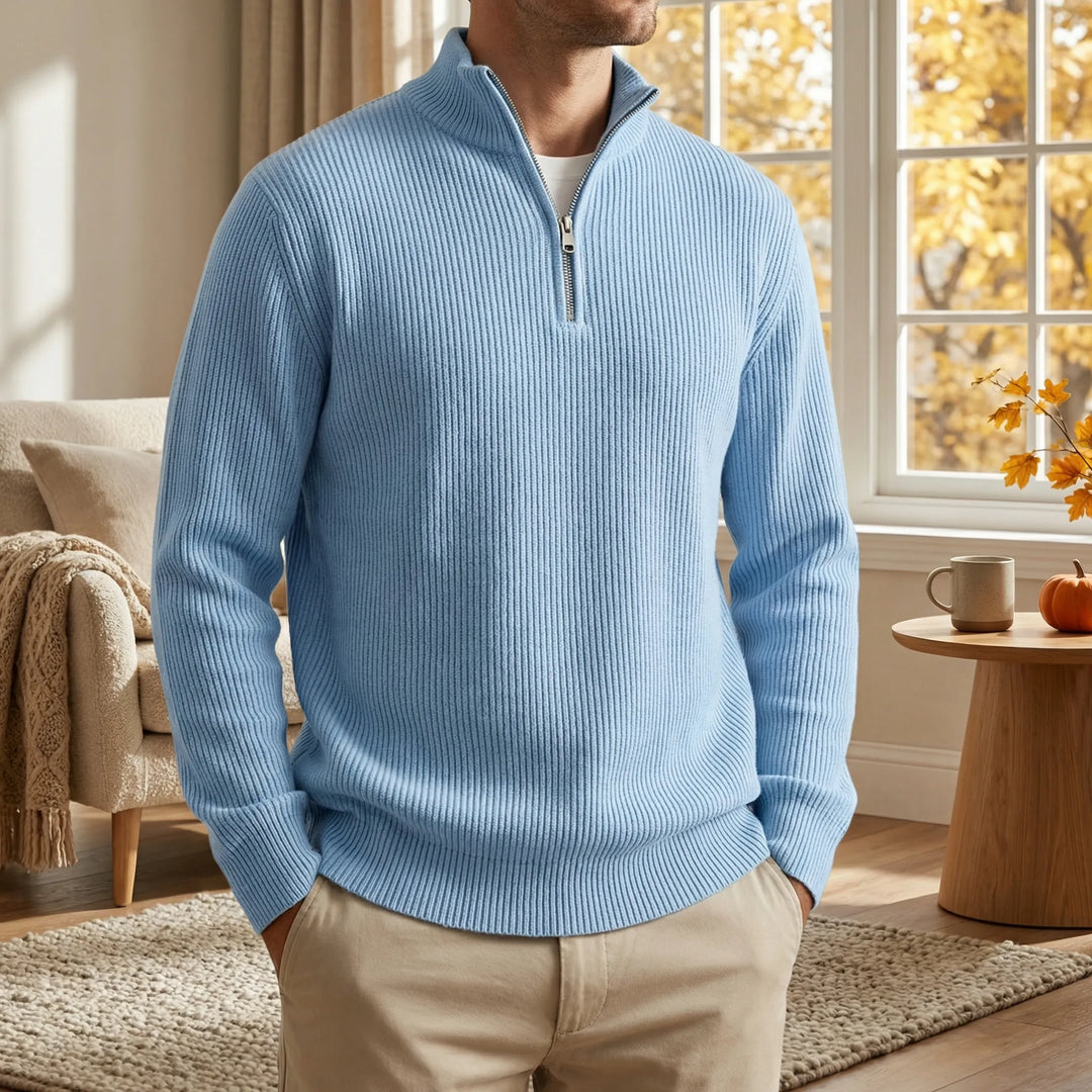 Homme en pull côtelé bleu clair à col zippé, mains dans les poches d'un pantalon beige, dans un salon d'automne. 2