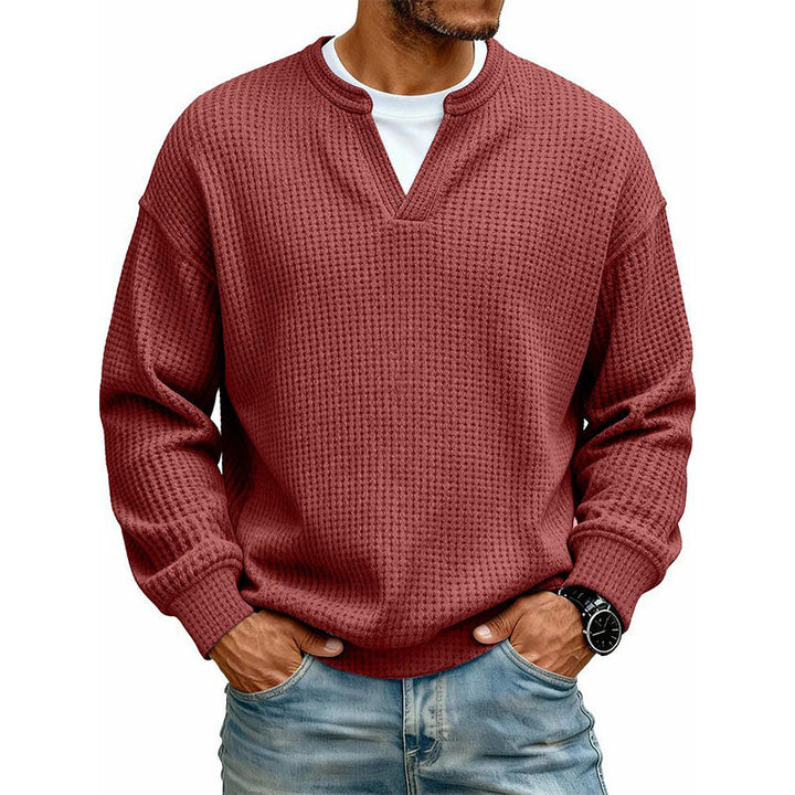 Pull gaufré rouge brique porté par un homme sur t-shirt blanc, mains dans les poches de son jean. 10