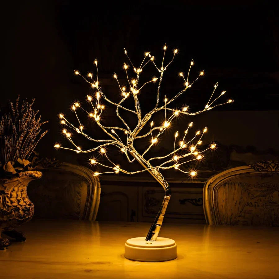 Lampe arbre allumée sur une table claire, dans une pièce sombre avec chaises sculptées et fleurs séchées 2