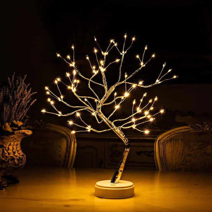 Lampe arbre allumée sur une table claire, dans une pièce sombre avec chaises sculptées et fleurs séchées 2