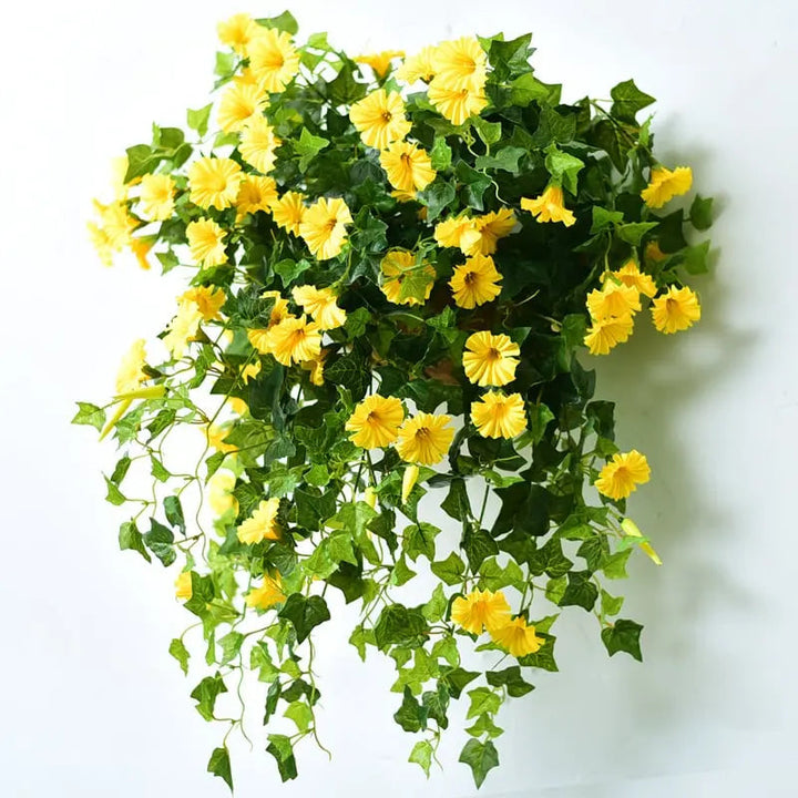 Gros plan sur une touffe de fleurs artificielles jaunes et de feuilles vertes lobées, appliquée contre un mur clair. 5