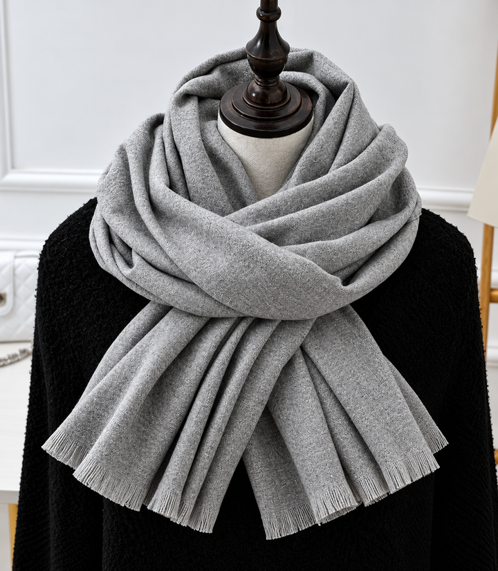 Écharpe gris clair à franges, drapée autour du cou sur un mannequin habillé de noir 1