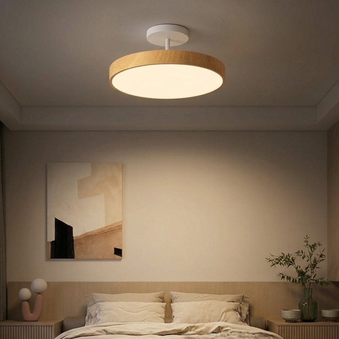 Plafonnier à cadre bois clair et platine blanche au-dessus d'un lit, dans une chambre aux tons beiges avec tableau abstrait. 7