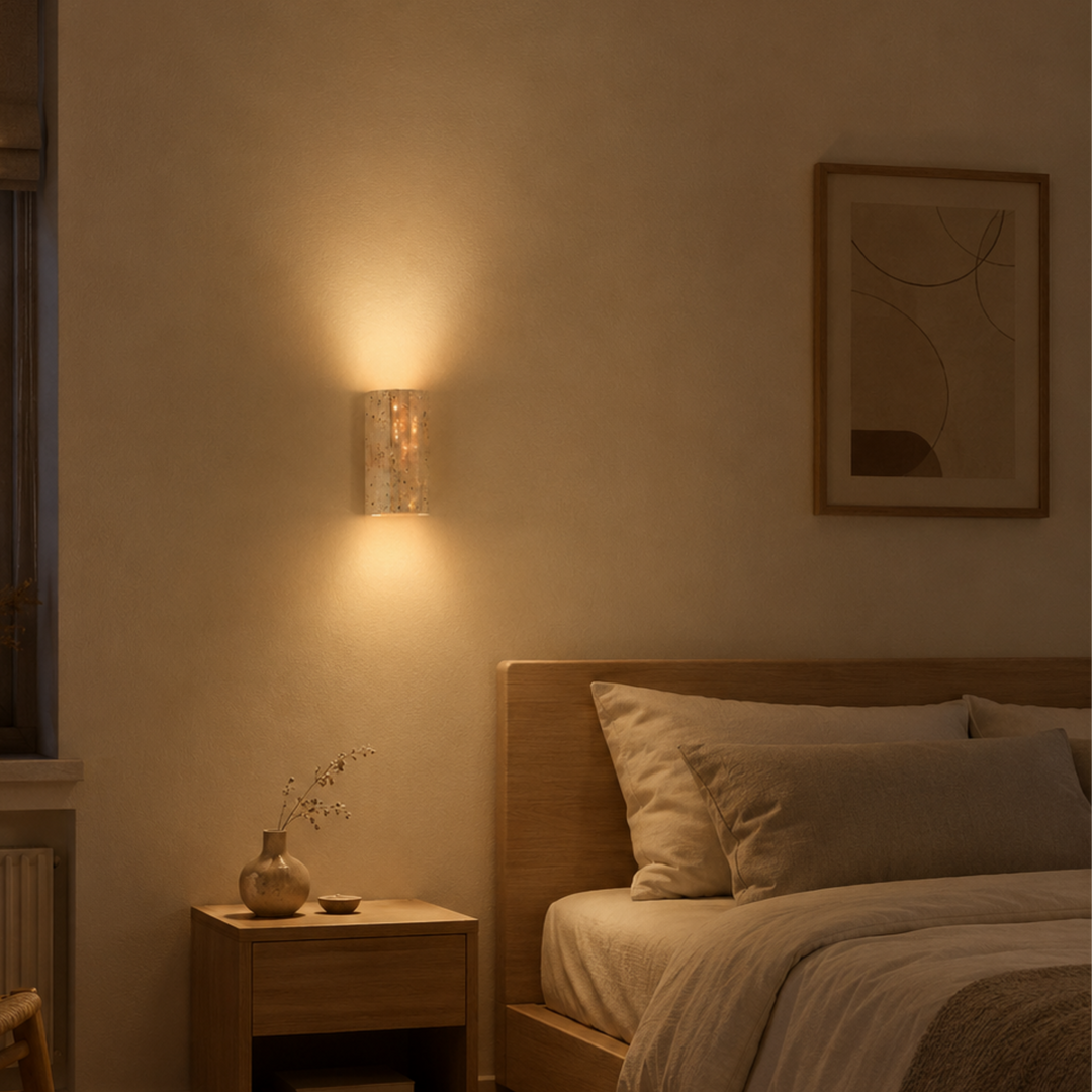 Applique en pierre allumée dans une chambre tamisée, au-dessus d'une table de chevet en bois, avec un lit aux draps clairs. 5