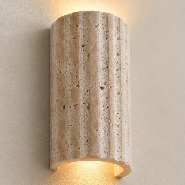 Gros plan sur la surface en pierre cannelée et poreuse de l'applique, allumée, avec la lumière chaude qui s'échappe par le haut et le bas. 4