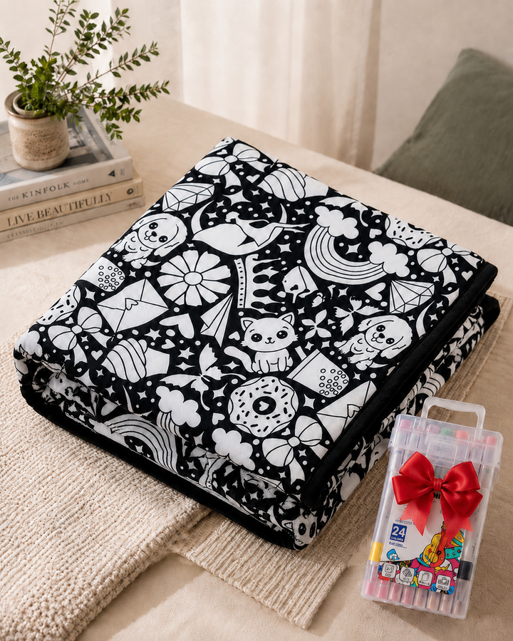 Plaid plié au motif de chats, chiens, arcs-en-ciel et beignets à colorier, près d'un coffret de marqueurs 7