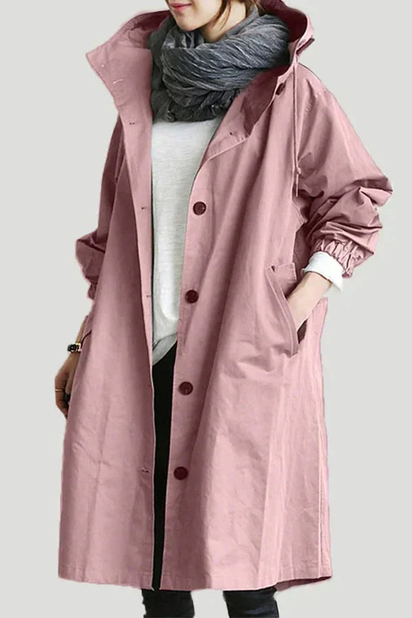 Trench rose poudré à capuche porté de face, boutonné avec des boutons foncés, haut blanc et écharpe grise. 13