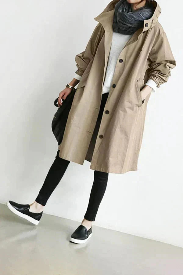 Trench beige à capuche porté de face, boutonné, avec haut blanc, écharpe grise, jean noir et baskets noires. 10
