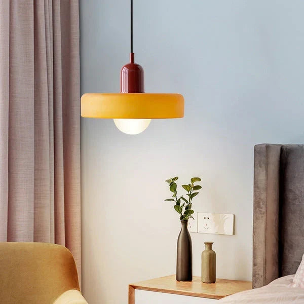 Suspension à abat-jour orange et capuchon bordeaux allumée dans une chambre, près d'une table de chevet avec vases. 16