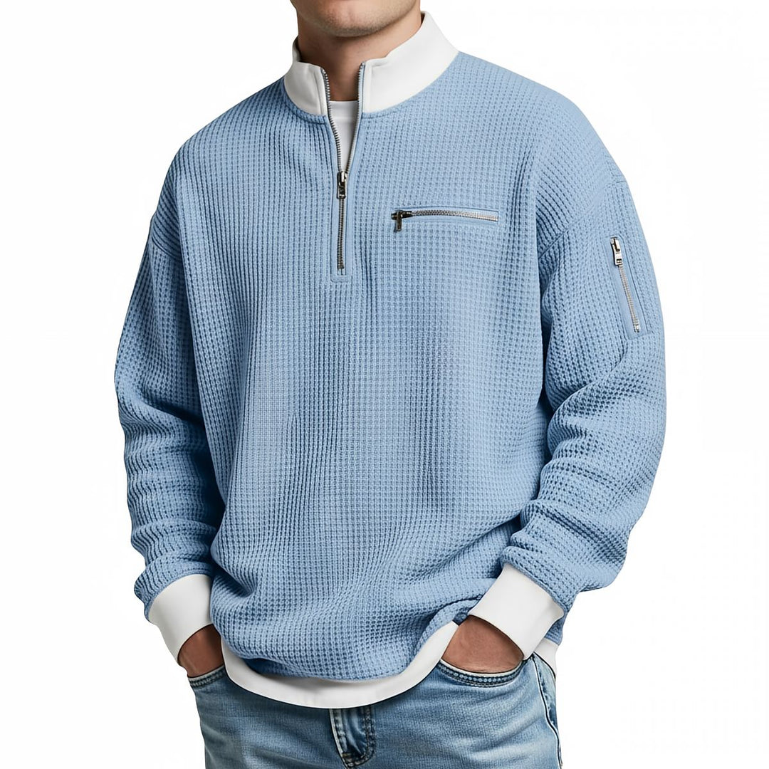 Pull gaufré bleu ciel à col zippé et poignets blancs, porté de face par un homme en jean. 4