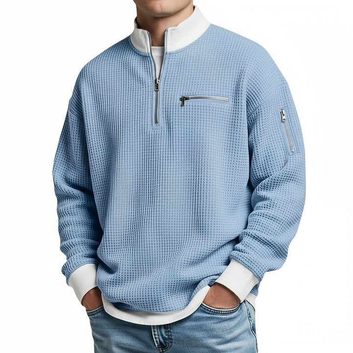 Pull gaufré bleu ciel à col zippé et poignets blancs, porté de face par un homme en jean. 4