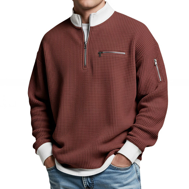 Pull gaufré rouge brique à col montant zippé, poche poitrine zippée, porté de face avec un jean. 11