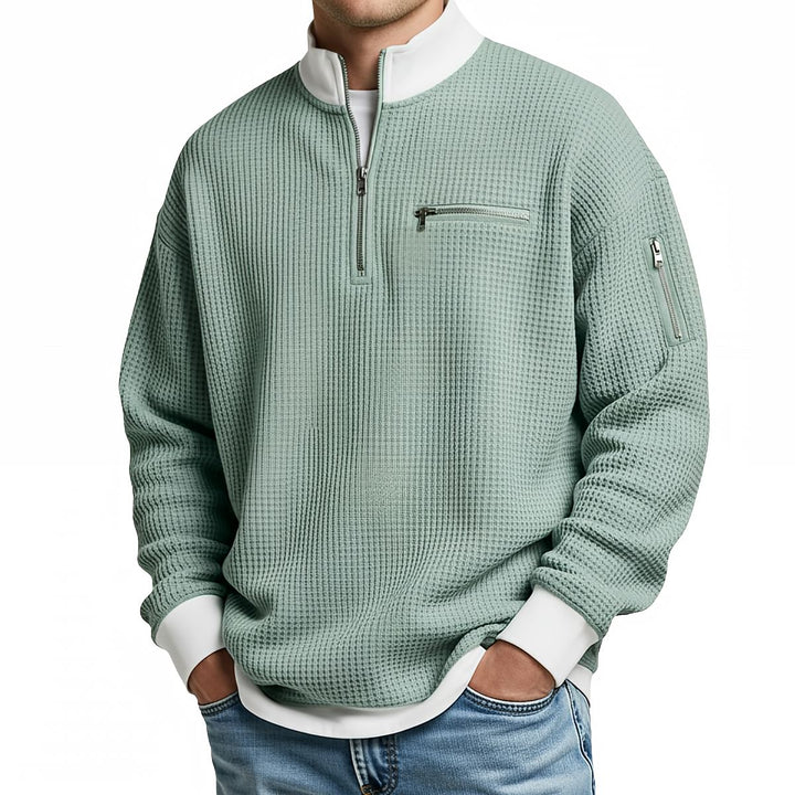 Pull gaufré vert clair à col zippé et bords côtes blancs, porté de face par un homme en jean. 6
