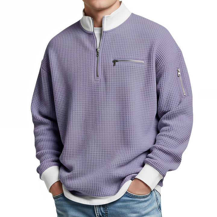 Pull gaufré violet lavande à col zippé et poignets blancs, porté de face par un homme en jean. 10