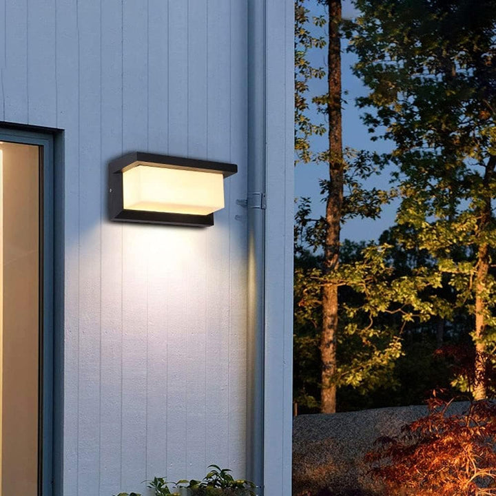 Applique à lumière blanche chaude sur un mur en lames blanches, avec une gouttière et des arbres 6