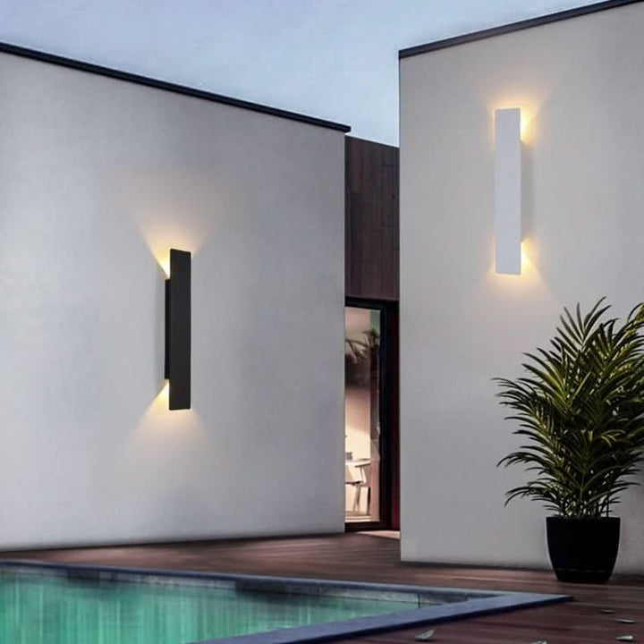 Une applique noire et une applique blanche sur des murs de terrasse au bord d'une piscine, près d'une plante en pot. 4