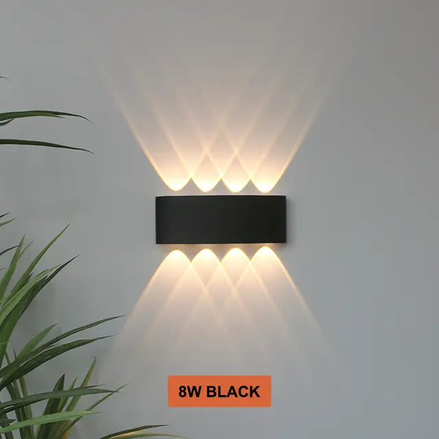 Applique noire à quatre faisceaux haut et quatre bas, éclairant un mur gris de motifs lumineux chauds entrecroisés. 13