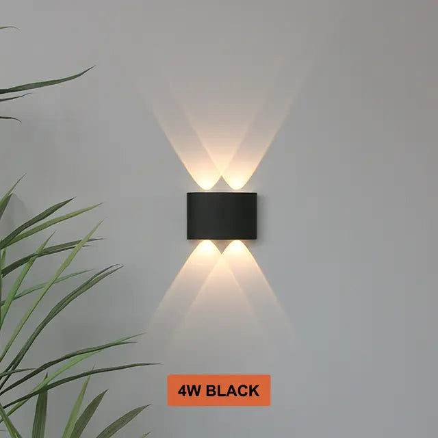 Applique noire à deux faisceaux haut et deux bas, allumée sur un mur clair près d'une plante, variante de coloris noire. 8