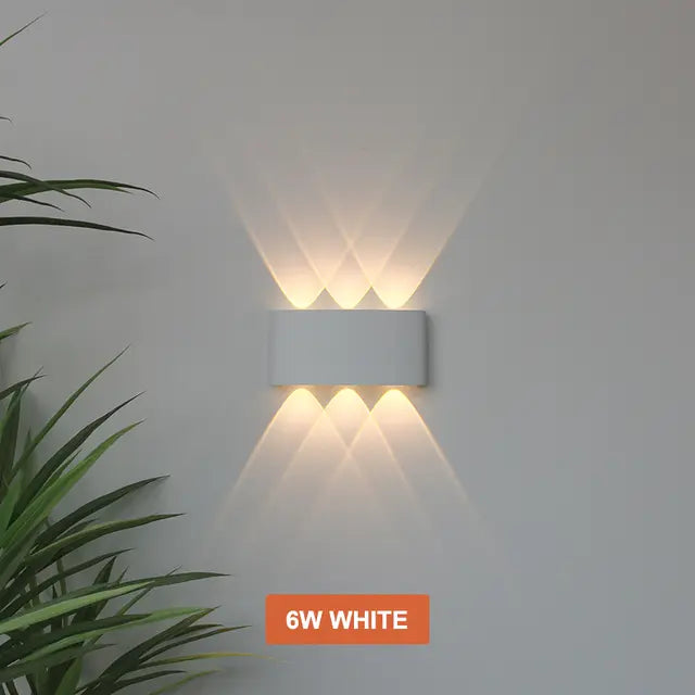 Applique blanche à trois faisceaux haut et trois bas, lumière chaude formant des motifs croisés sur le mur. 9