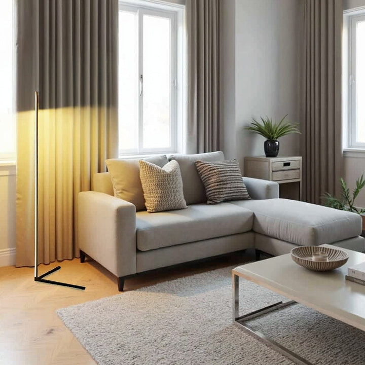 Lampadaire fin allumé près de rideaux beige et d'un canapé d'angle clair, dans un salon lumineux 10