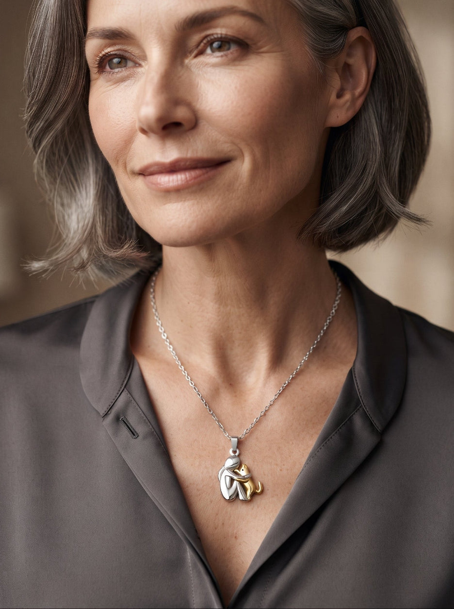 Portrait d'une femme aux cheveux gris mi-longs, chemisier gris, portant le pendentif argenté et doré sur une chaîne argentée. 10