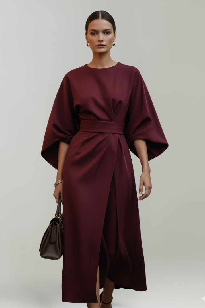 Robe bordeaux portée de face par un mannequin, jupe croisée fendue et sac brun foncé 11