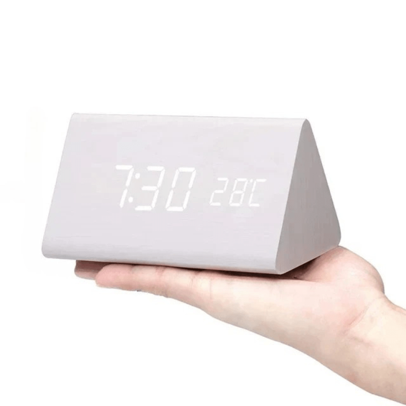 Réveil triangulaire blanc effet bois tenu sur la paume, affichage LED blanc de l'heure et de la température. 11