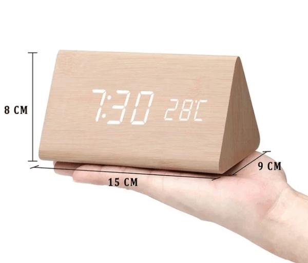 Réveil triangulaire en bois clair posé sur une main, avec cotes indiquées de 8, 9 et 15 centimètres. 7