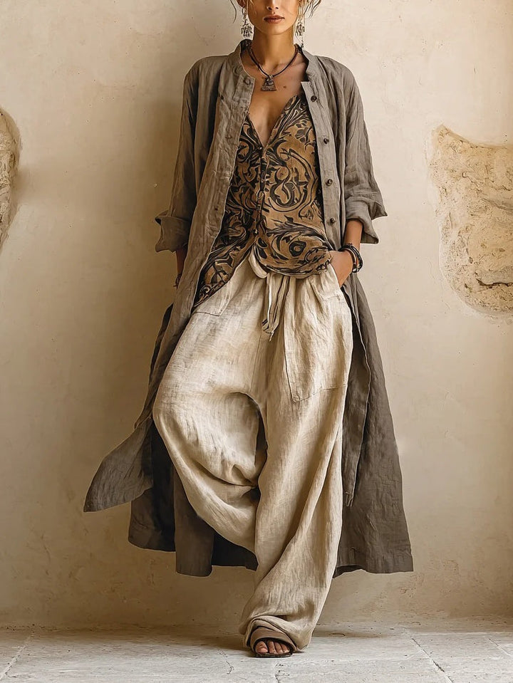 Femme de face portant les trois pièces : long manteau en lin gris-brun ouvert, top à motifs, pantalon ample beige 1