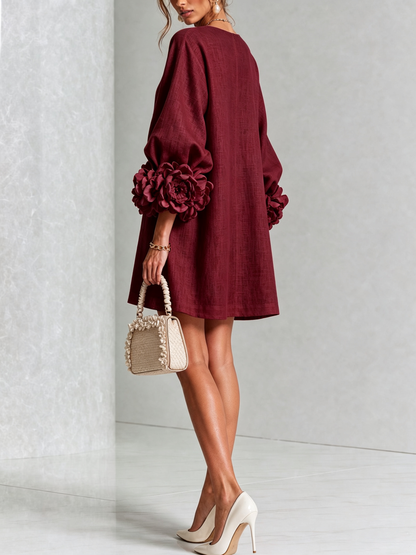 Robe bordeaux vue de dos et de trois quarts, coupe évasée, rosettes aux poignets, sac beige à volants. 40