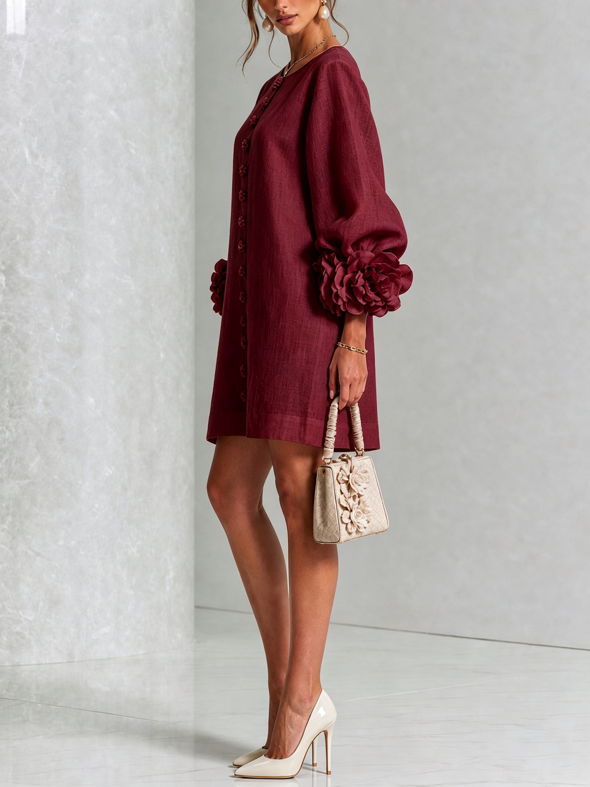 Robe bordeaux portée de profil, manche ballon avec grosse rosette au poignet, sac beige fleuri et escarpins clairs. 39