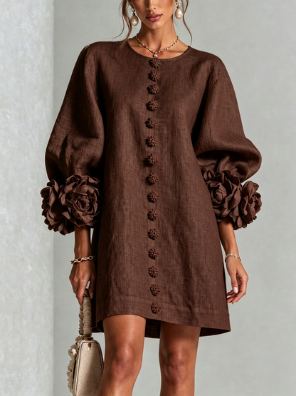 Robe marron chocolat portée de face, boutons fleurs alignés et manches ballon terminées par de grandes rosettes. 31