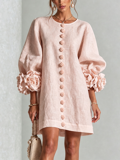 Robe rose poudré portée de face, boutons fleurs sur toute la hauteur et manches ballon à grandes rosettes. 24