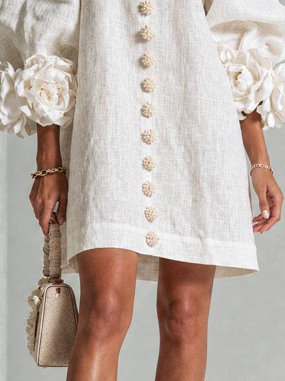 Gros plan sur le bas de la robe écrue: boutons fleurs, ourlet droit et roses aux poignets. 16