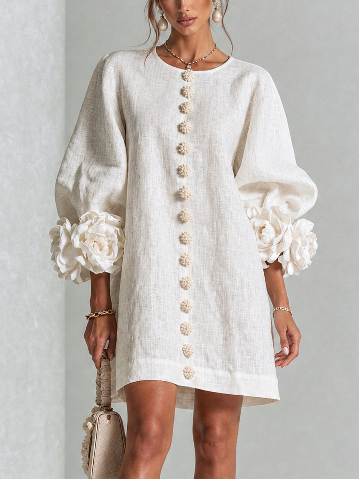 Robe blanc cassé portée de face, boutons en fleurs au devant et grosses fleurs aux poignets 1