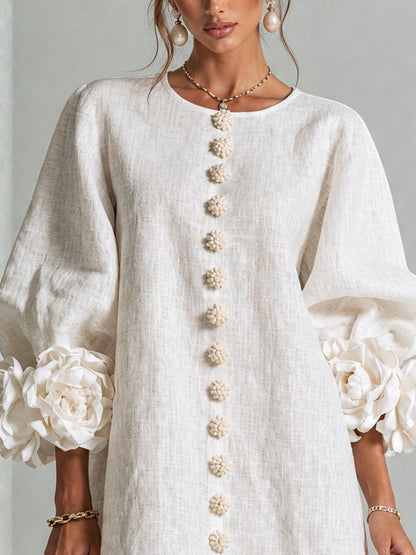 Gros plan sur le buste de la robe écrue: encolure ronde, boutons fleurs en rangée et roses aux manches. 15