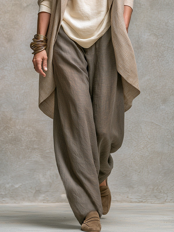 Plan du bas de la tenue montrant le pantalon taupe très ample, ses jambes larges et le bord arrondi de la veste. 5