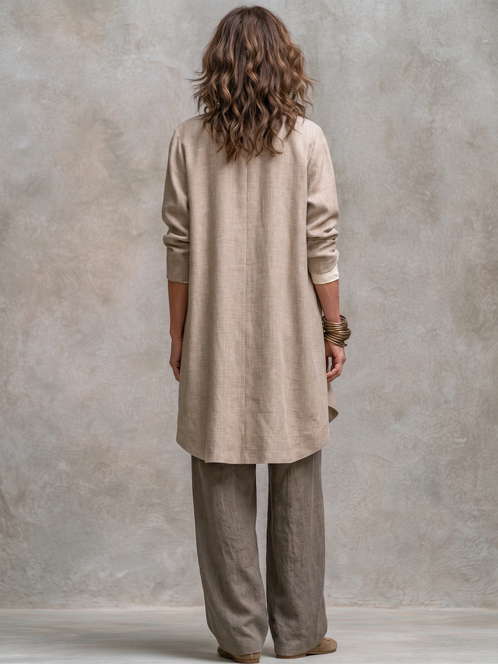 Femme de dos montrant la veste longue beige au bas arrondi et au pli central, avec le pantalon large taupe. 6