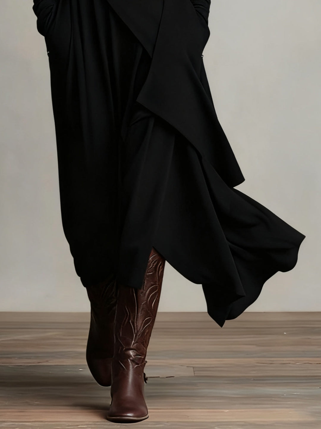 Détail du bas asymétrique de la robe noire, jupe fluide et bottes brunes gravées 8