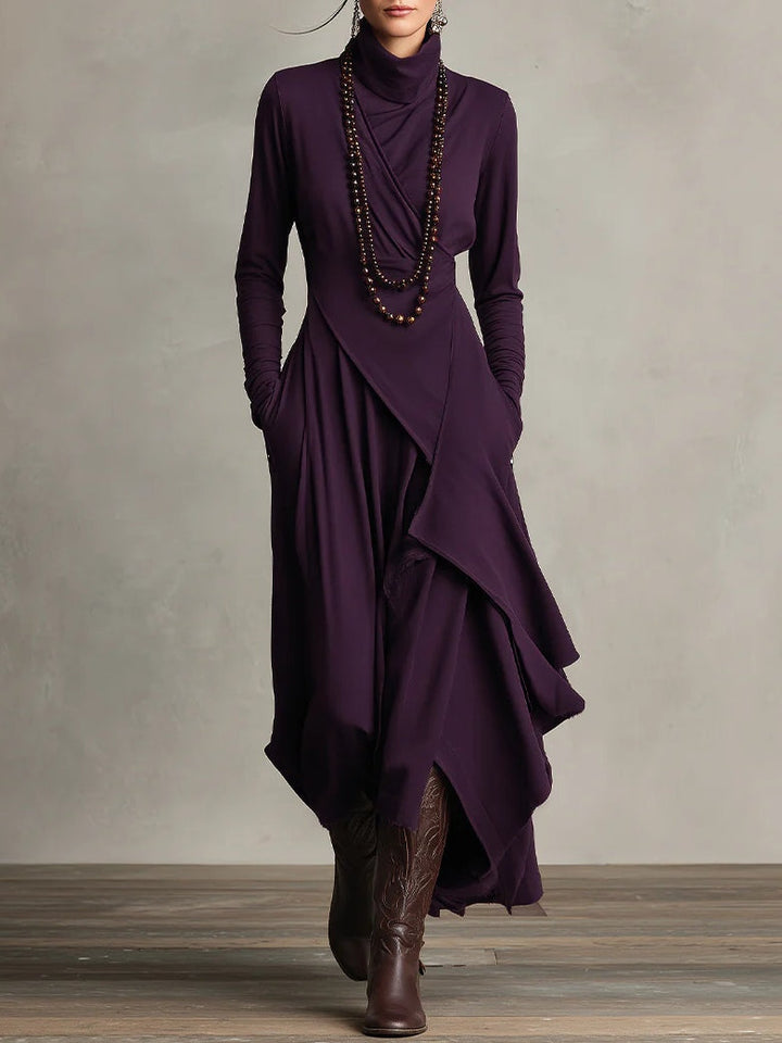 Femme portant la robe violet foncé de face, avec long collier de perles et bottes brunes 1