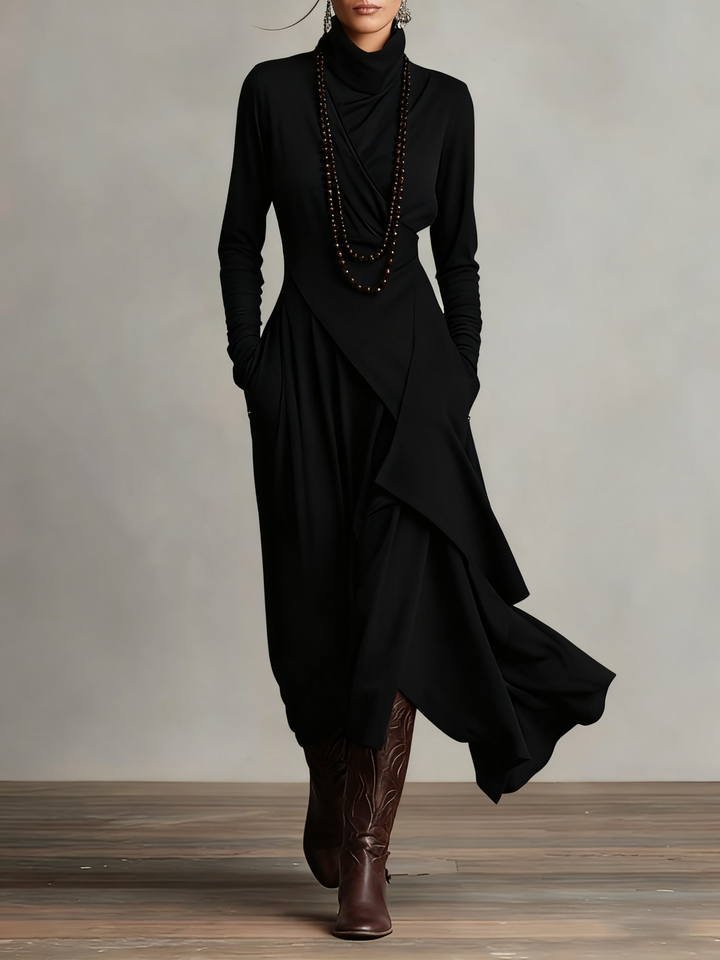 Robe noire portée de face, col roulé drapé, long collier de perles et bottes brunes 6