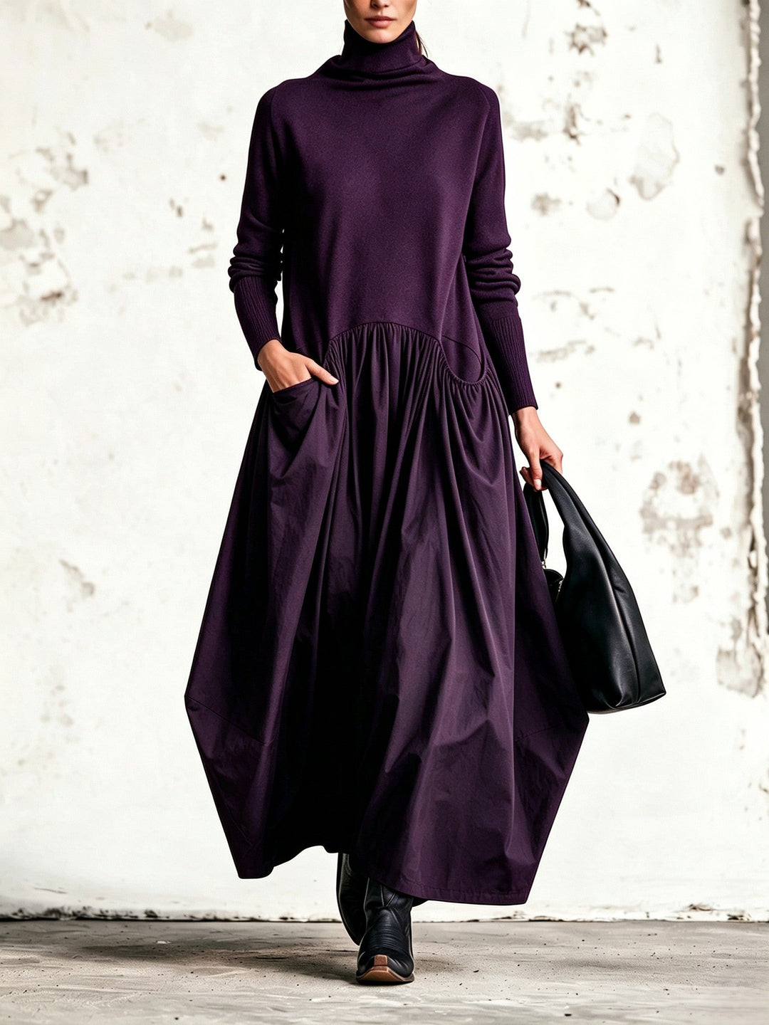 Robe violet foncé portée de face, col montant, jupe ample plissée, bottes et sac noirs 7