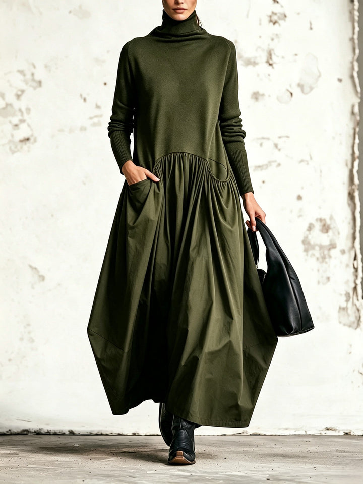 Robe vert olive portée de face, col montant, jupe ample plissée et main dans la poche 4
