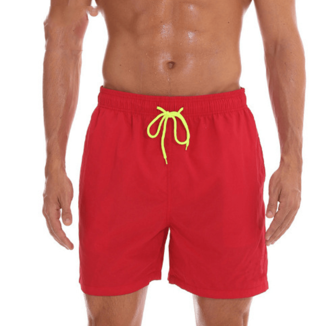 Short de bain rouge vif porté par un mannequin à la peau mouillée, cordon jaune fluo noué, bras le long du corps. 10
