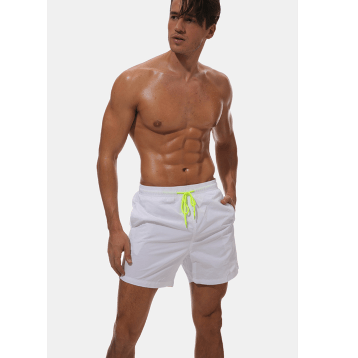Mannequin en short de bain blanc, cordon jaune fluo noué, une main dans la poche, regard de côté. 12