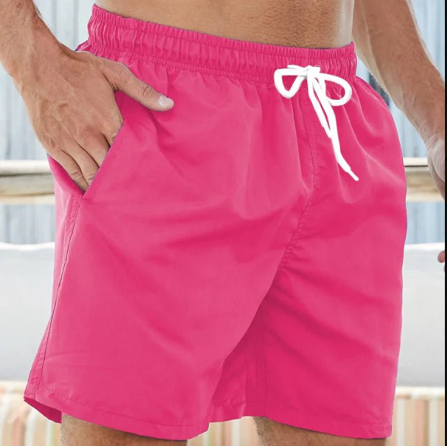 Short de bain rose vif porté, cordon blanc noué à la taille, une main glissée dans la poche latérale. 3