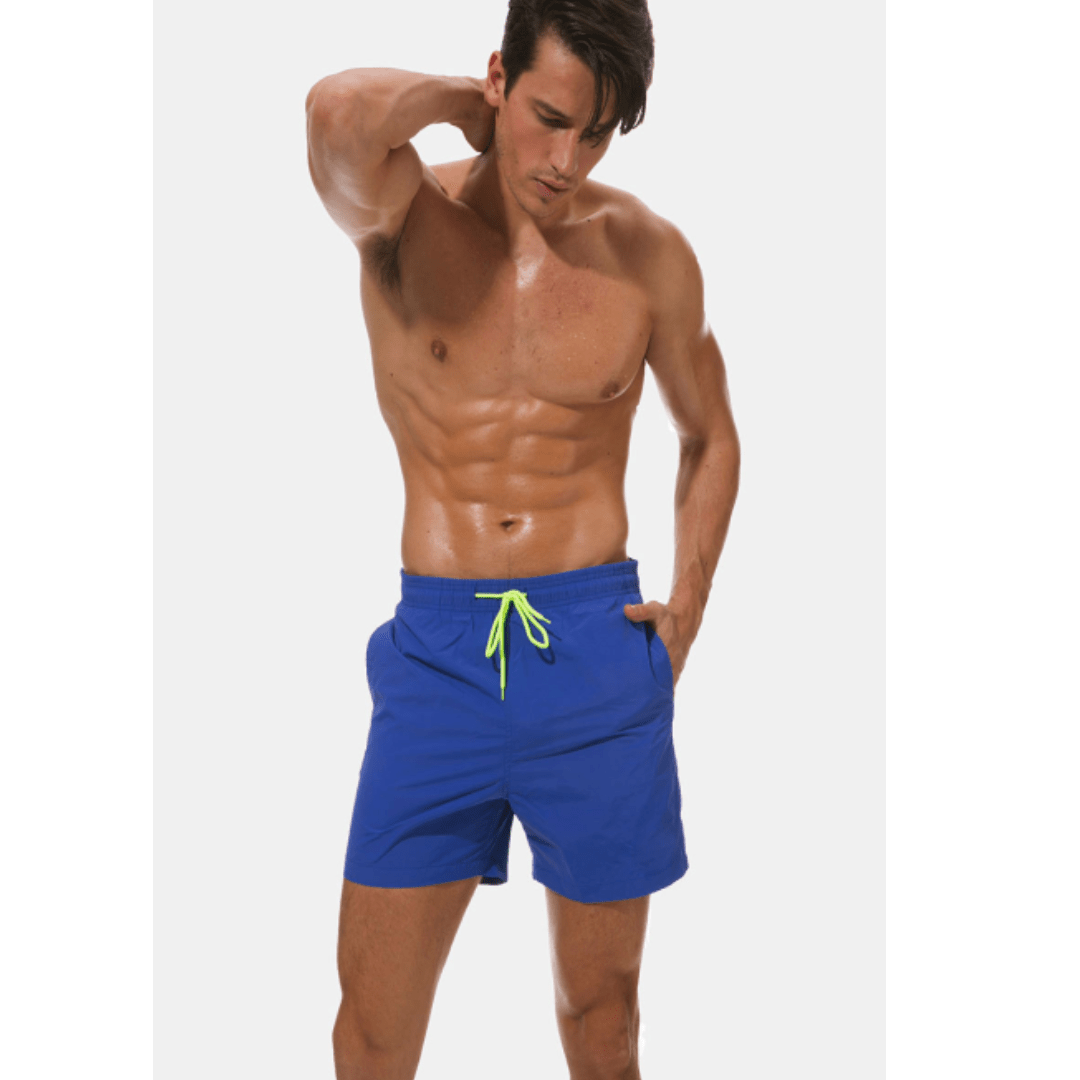 Mannequin en short de bain bleu roi, cordon jaune fluo, main dans la poche, posant sur fond clair. 4