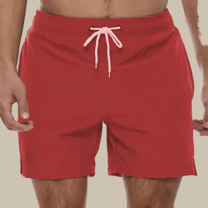 Vue de face d'un short de bain rouge porté, cordon rose pâle noué et fentes latérales à l'ourlet. 9
