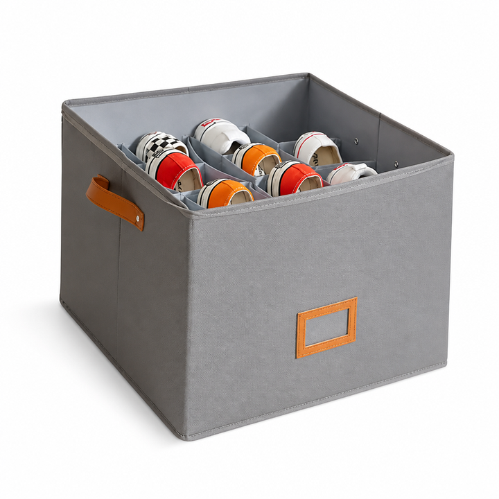 Version grise de la boîte sur fond blanc, avec poignée et étiquette orange, contenant des baskets rangées dans ses compartiments. 5
