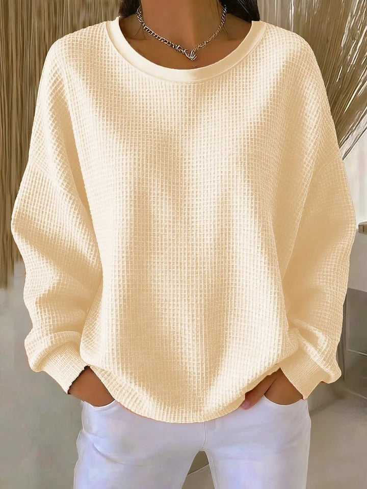 Pull gaufré beige clair à col rond et manches longues, porté mains dans les poches avec un pantalon blanc. 4